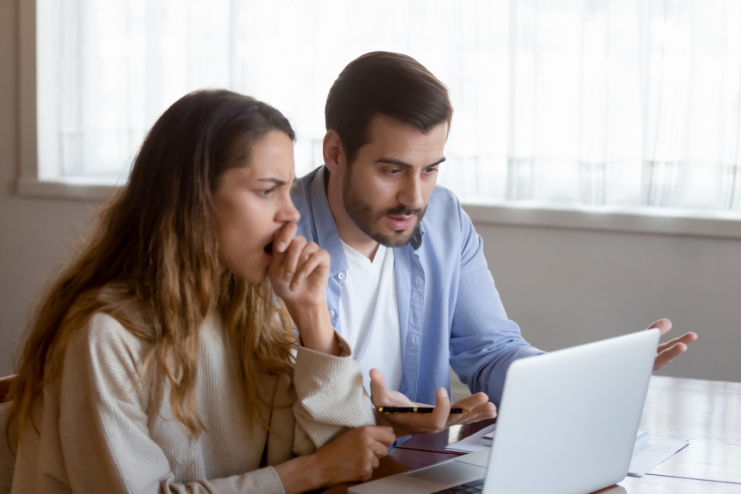 Stressed,Young,Couple,Sitting,At,Table,,Looking,At,Laptop,Screen.